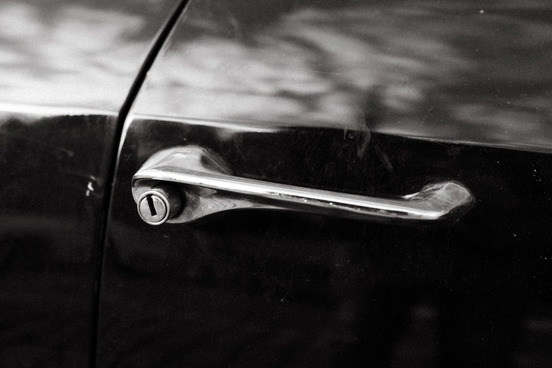 Close-up of a vintage car door handle captured in a classic black and white style.